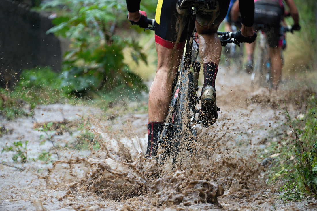 cyclist riding through mud on mountain bike