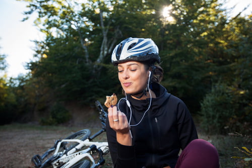 female cyclist eating during bike ride. cycling nutrition