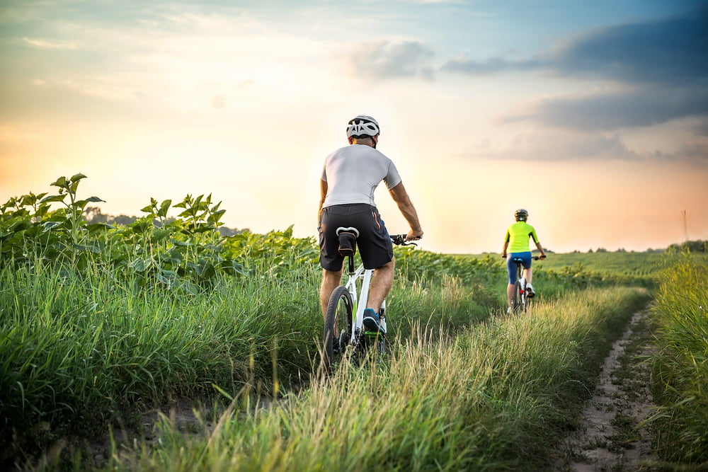 couple riding bikes through a field